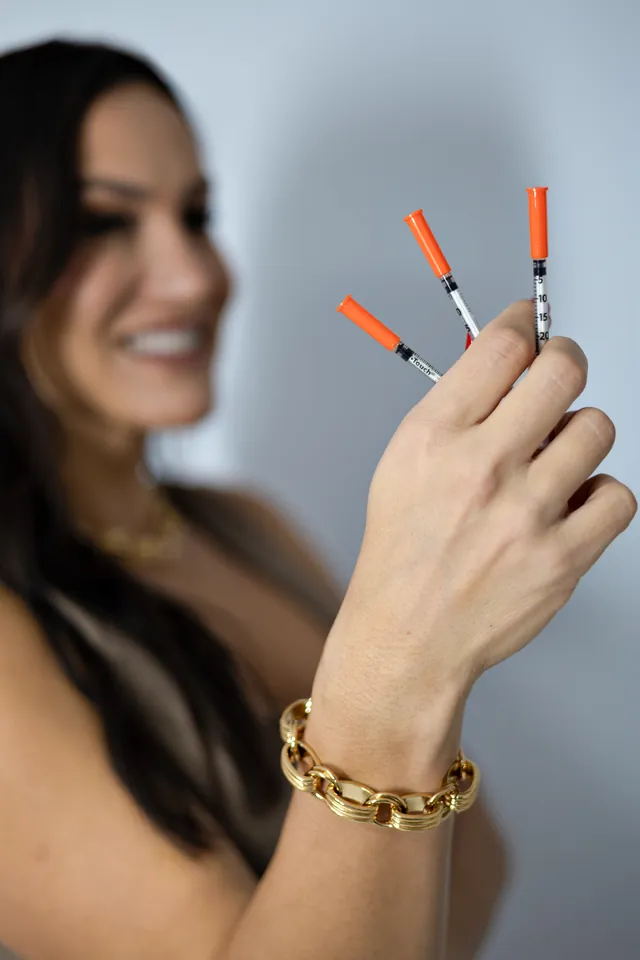 Three filler syringes held up beside Bianca's smile